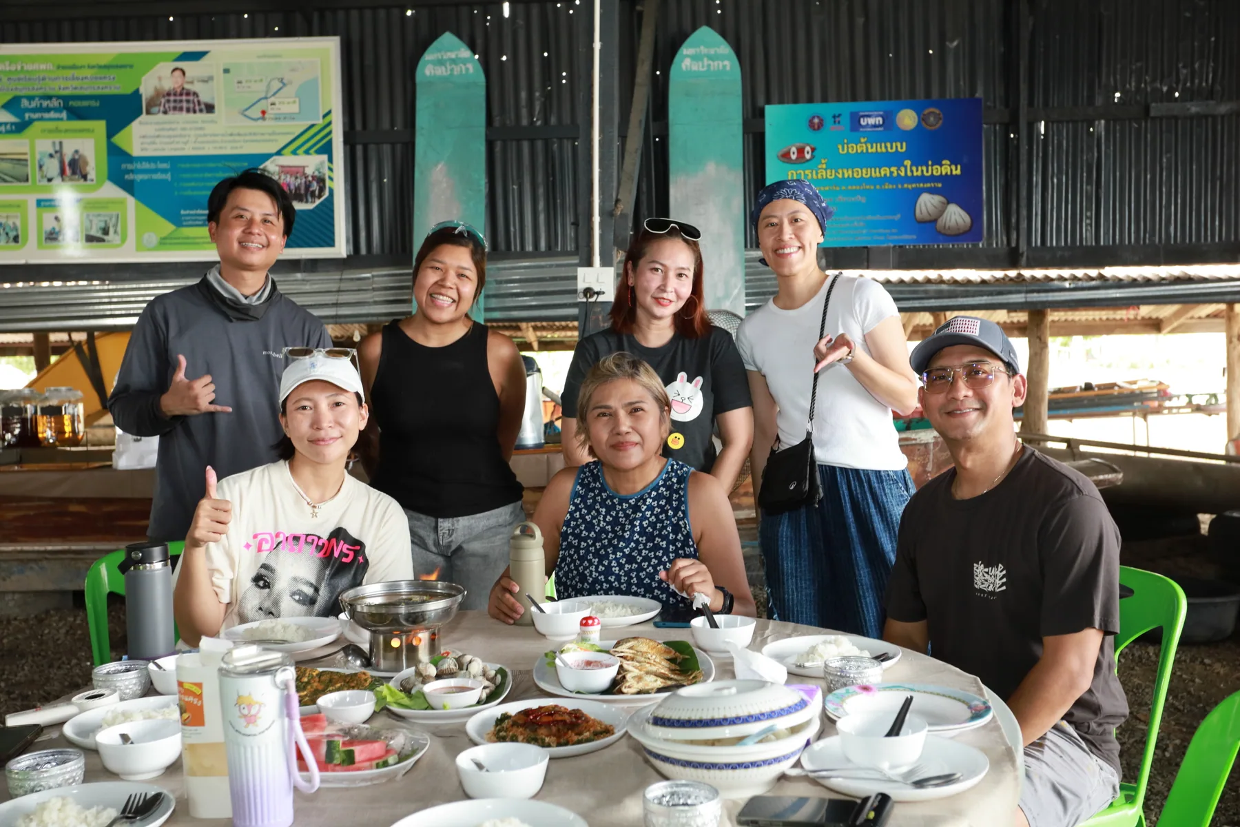 กลุ่มผู้มาเยือนยิ้มถ่ายภาพร่วมกันรอบโต๊ะอาหารท้องถิ่นภายในฟาร์ม